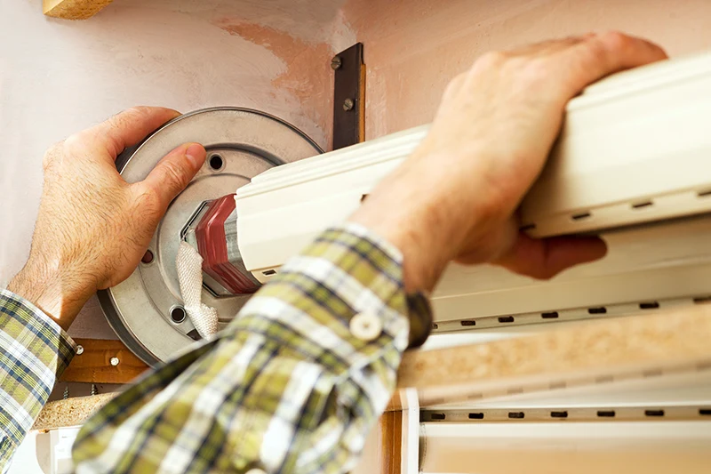 Ein Handwerker befestigt einen Rolladen am Fenster