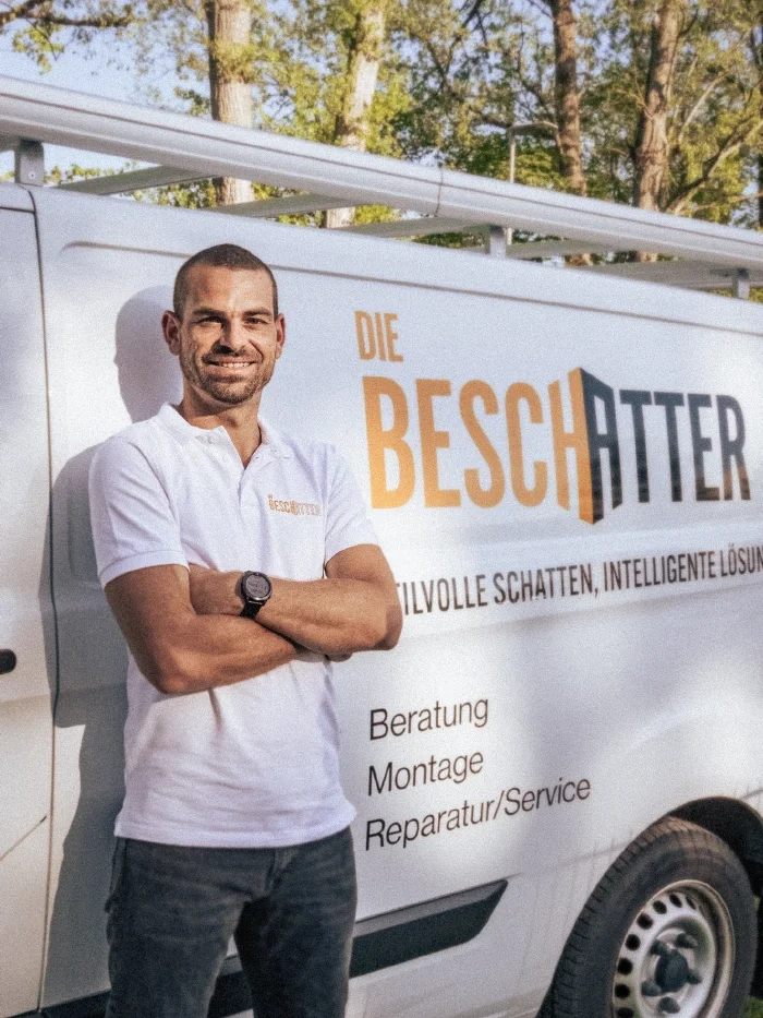 Kevin Martinelli steht vor dem Bus der Beschatter und lächelt in die Kamera